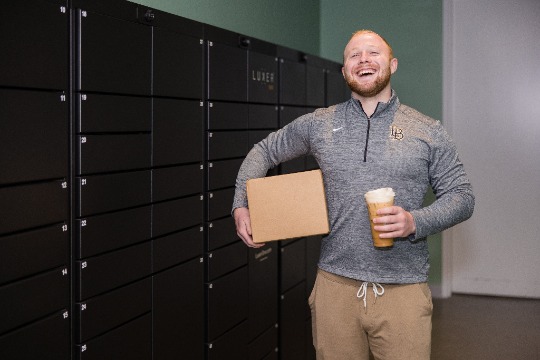 College student smiling infront of Luxer One Lockers