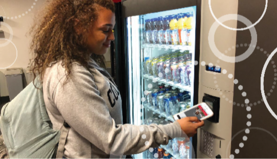Woman using Transact Mobile Credential on vending machine